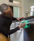 Man using Stainless Steel Cleaner 2 Pack 16 Oz Streak Free Polish For Kitchen Sinks Stoves And Metal Appliances Refrigerator.