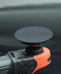 Close-up of a black polisher with Two Pack Rotary Backing Plate With Hook And Loop Surface For Polisher Sander 5 Inch 5 By 8 By 11 Thread Orange PU Soft Backing Pad For Easy Sanding Polishing Buffing And Finishing, showcasing a smooth hook-and-loop surface.