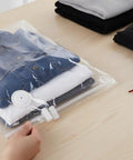 Hand using 40 Pack Vacuum Storage Bag Sealing Clips With Sliding Grip Zipper Bag Sealer on clothes in clear vacuum bag.