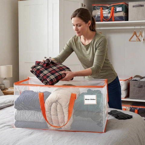 Woman organizing winter clothes into Extra Large Clear Moving Bags 2 Pack Heavy Duty Totes With Reinforced Handles And Label Pocket.