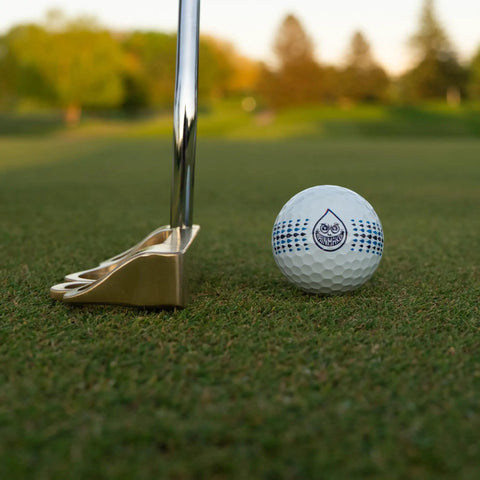 No-Nonsense 3 Piece Urethane Golf Ball With Spin And Feel For Sharp Shot Shaping on grass next to putter