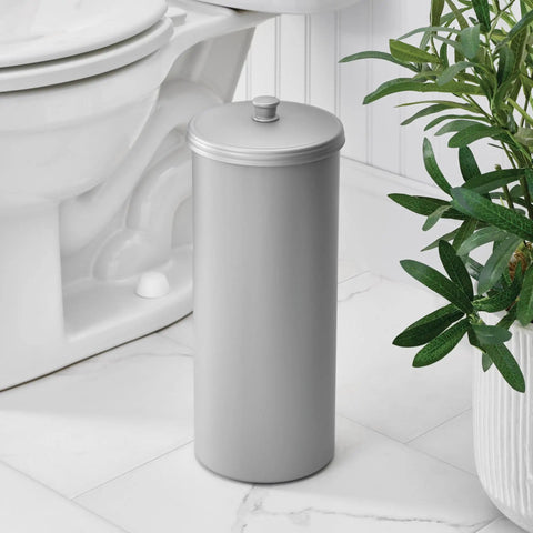 Discreet Floor Standing Toilet Paper Holder With Lid For 3 Extra Rolls In Silver beside a toilet in bathroom.