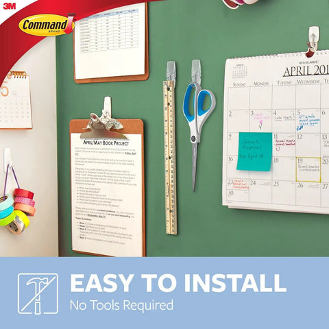 Medium Clear Wire Toggle Hooks With Adhesive Strips Set Of 6 Hooks And 8 Strips For Damage Free Hangin On Walls, Doors, Cabinets Or Closets Holds Up To 2 Lbs Easy No Tools Needed Great For Quick Organization And Storage, shown in use organizing calendars and tools on green board