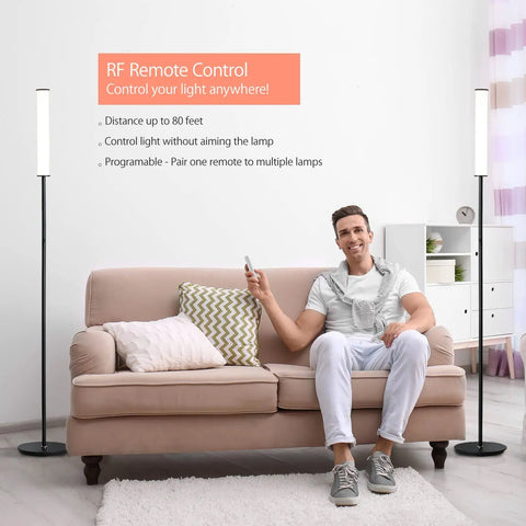 Man using remote to control Dope Cylinder LED Floor Lamp with Full Range Dimming in living room, black finish