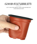 Hand holding 100 Pack Red 4 Inch Plastic Plant Pots For Seed Starting And Seedlings Lightweight Reusable Nursery Pots With Drainage Holes