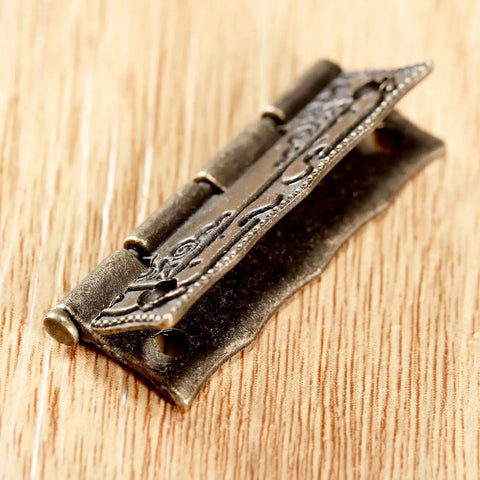 Close-up of decorative 2 Pack Cabinet Door Hinges 36x23mm resting on wood surface, emphasizing intricate design and rugged style