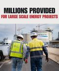 Two workers in high-visibility jackets and helmets walking on an energy project site with large structures in the background.