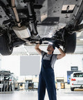 Mechanic working under car lift inspecting suspension components at auto repair shop