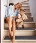 Mother and child sitting on stairs with 15 Piece Indoor Stair Treads For Wooden Steps Non Slip Carpet Runner Mats With Gray Stripe Pattern.