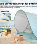 Pop Up Baby Beach Tent with UV Protection showing triple sandbag design and ground stakes for stable anchoring on sand.