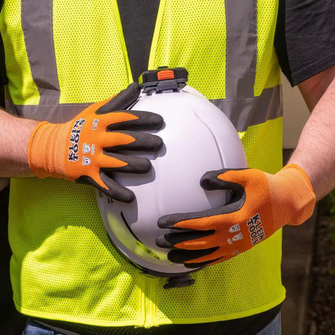 Person wearing Rugged Knit Dipped Work Gloves With Nitrile Coating For Cut Resistance ANSI A1 holding a white helmet