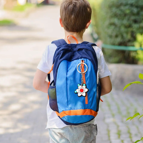 Child with blue backpack adorned with 20 Pack Science Party Keychains Set Colorful Silicone Keyrings for Backpack and School Decor