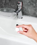 Top Shelf Rubber Sink Overflow Cover Cap 3 Pack White Silicone Drain Guard For Kitchen And Bathrooms Easy Snap Install Leak Blocker being held over a sink.