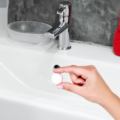 Top Shelf Rubber Sink Overflow Cover Cap 3 Pack White Silicone Drain Guard For Kitchen And Bathrooms Easy Snap Install Leak Blocker being held over a sink.