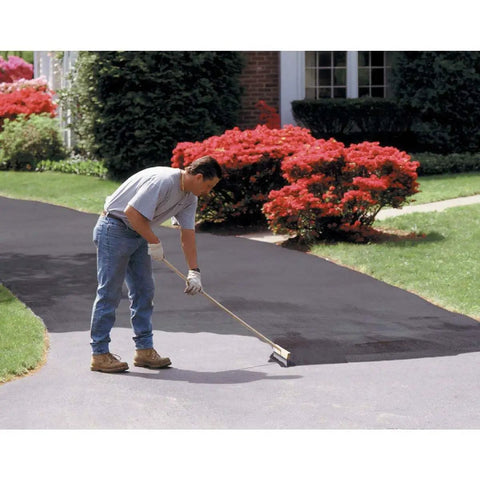 Man applying EZ Stir Rubber Driveway Asphalt Filler Sealer For Cracks Up To One Eighth Inch Quick Patch For Blacktop on driveway.
