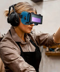 Boss Grade Auto Darkening Welding Goggles Heavy Duty Industrial Safety Glasses With Lightning Shade Switch For Grinding Soldering And Precision Steel Fabrication In Navy Blue worn by a woman using tools.