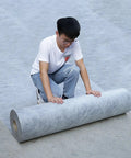 Kickass Heavy Duty Waterproof Membrane And Roof Underlay Roll For Walls Floors And Tile Bedding Fifty Five Meter Gray Sheet being unrolled by a person.