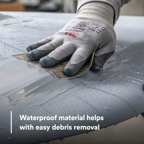 Hand using Wetordry Sandpaper Sheets 800 Plus Grit 9 In By 11 In Pack Of 50 for auto sanding on wet car surface with gloves.