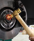 Drop Forged Solid Brass Non Sparking Hammer 20 Oz with Hickory Wood Handle used on metal part, showcasing non-slip grip and durability