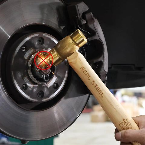 Drop Forged Solid Brass Non Sparking Hammer 20 Oz with Hickory Wood Handle used on metal part, showcasing non-slip grip and durability
