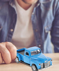 Man holding sky-blue pickup truck figurine vintage alloy car model toy; retro ornament for Christmas table centerpiece and New Year decor.