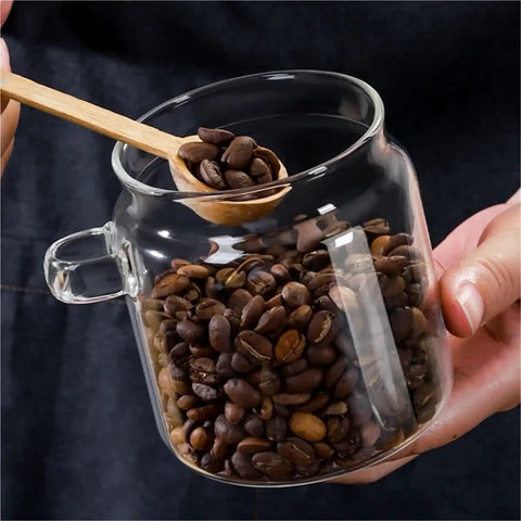 Go Ahead And Upgrade Your Countertop Setup With This Solid Clear Glass Storage Jar Featuring An Airtight Sealed Kitchen Canister And Wooden Spoon For Coffee Beans 900Ml Capacity Handles Dry Goods Smoothly And Looks Dope. Image shows a glass jar filled with coffee beans and a wooden spoon.