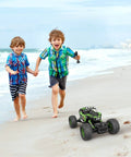 Two children playing on the beach with All Terrain RC Monster Truck For Kids With Upgraded Lifting Function 2.4GHz Four Wheel Drive Remote
