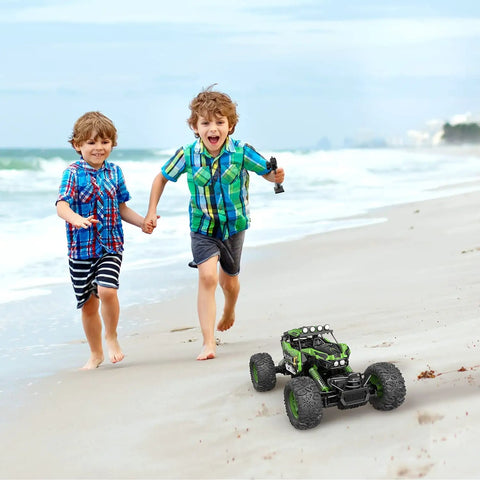 Two children playing on the beach with All Terrain RC Monster Truck For Kids With Upgraded Lifting Function 2.4GHz Four Wheel Drive Remote