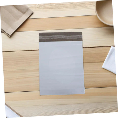 White Poly Mailer Bags 100 Pack 10x14 Inch Waterproof Self Seal Envelopes on a wooden table