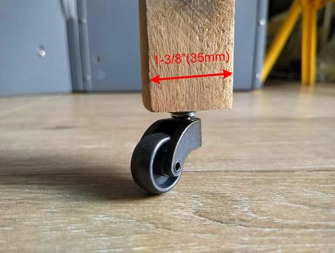 Front view of LUXUFUL 1-inch swivel stem ball caster wheel, vintage black, mounted under a wooden furniture leg.