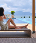 Person sitting on poolside bench with scenic mountain and pool view in background, adjacent to pergola post.