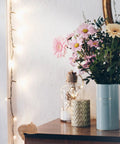 Dog And Bear Shaped Silicone Table Corner Protector on wood table corner with flowers and fairy lights for furniture safety.