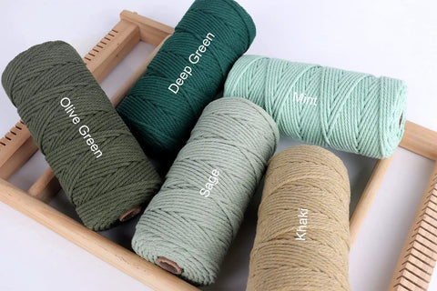 Five spools of Natural Macrame Cord in colors Olive Green, Deep Green, Sage, Mint, and Khaki on a wooden tray.
