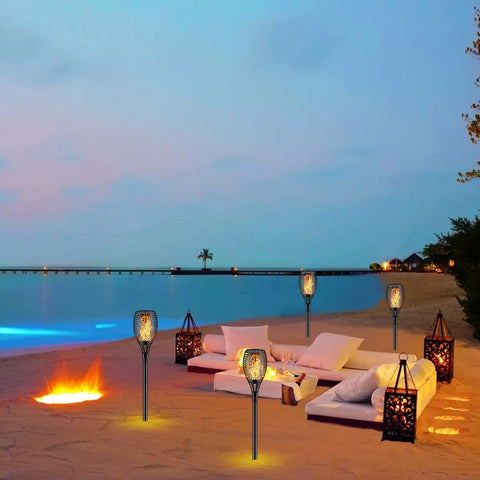 Beach setting with Solar Torch Light With Flickering Flame Dancing Flame Outdoor Lanterns Waterproof Garden Stake Lights Dust To Dawn Solar Powered Set Of 4 Eco Friendly Backyard Party Lighting For Patio Camping.