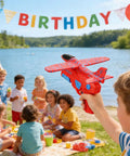 Hand Launched Foam Airplane Toy For Backyard Fun in child's hand at lake birthday party with kids in background.