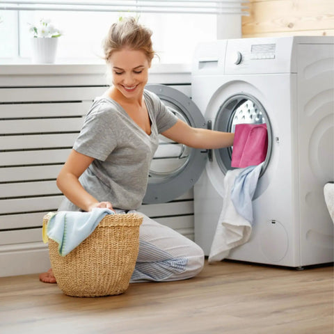 Woman placing a peach pink flannel heating pad replacement cover into a washing machine for cleaning.