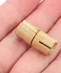 Smooth Operator Brass Concealed Barrel Hinges Six Piece Kit shown in hand, highlighting compact size and brass material.