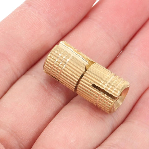 Smooth Operator Brass Concealed Barrel Hinges Six Piece Kit shown in hand, highlighting compact size and brass material.