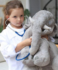 Child in Kids Lab Coat Doctor Costume For Halloween And Career Day Realistic White Coat For Boys And Girls Ages 7 To 9 examining toy elephant