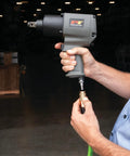 M627 3 Quarter Inch Drive Heavy Duty Impact Wrench With Aluminum Housing in hand at an auto shop entrance