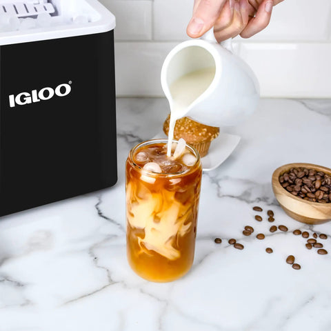 Person pouring milk into iced coffee next to Portable Countertop Ice Maker With Self Cleaning Produces 26 Lbs A Day Ice Ready In 6 To 8 Minutes Includes Ice Scoop And Basket Compact Desktop Unit For Home Office Or Parties