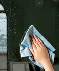 Puomue blue microfiber cleaning cloth, 12x16 inches, wiping a glass window.