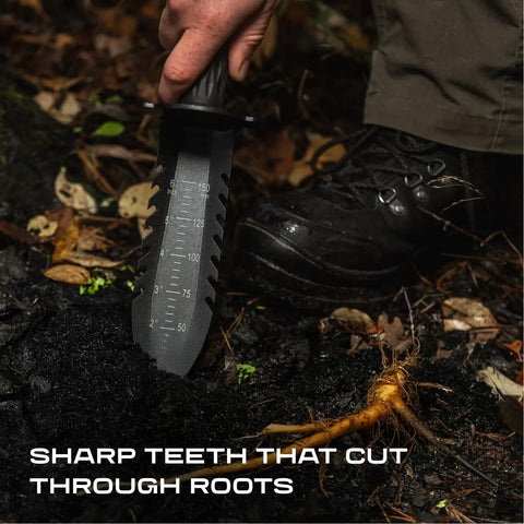 Hand holding Beefy Heavy Duty Metal Detecting Shovel With Double Serrated Blade cutting through roots in soil.