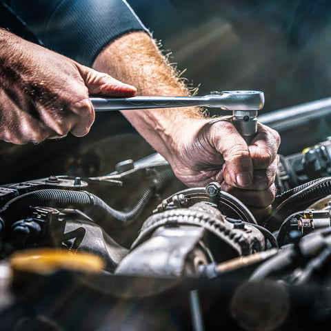 Mechanic using tool near car engine, illustrating Heavy Duty Cleaning Wipes 260 Count Bulk Pack With Dual Texture For Hands And Surfaces.
