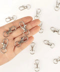 Hand holding silver clasps from Heavy Duty Metal Lobster Claw Clasp Set With Key Rings And Clips For Crafting 50 Clasps 25 Clip Hooks