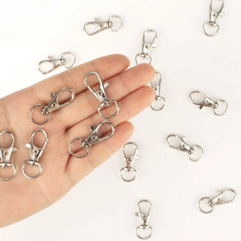 Hand holding silver clasps from Heavy Duty Metal Lobster Claw Clasp Set With Key Rings And Clips For Crafting 50 Clasps 25 Clip Hooks