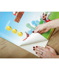 Hands applying Super Fun New Super Mario Bros Peel And Stick Wallpaper Border For Awesome Kids Bedrooms In Red Blue Green Removable