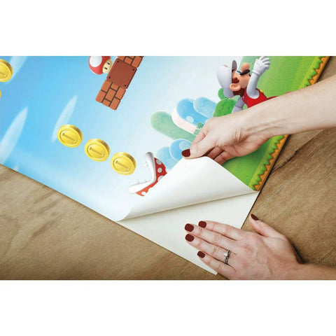 Hands applying Super Fun New Super Mario Bros Peel And Stick Wallpaper Border For Awesome Kids Bedrooms In Red Blue Green Removable