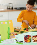 Kinggrand 13-piece Montessori toddler kitchen tools set on a lime-green cutting board; kid-safe wooden and plastic utensils.