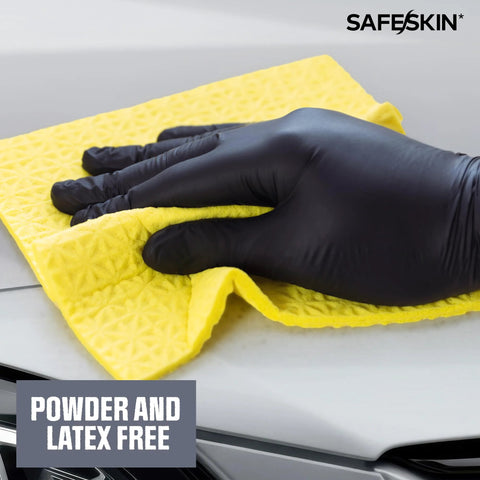 Safeskin black nitrile disposable glove on a hand wiping a car hood with a yellow cloth